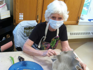 Woman with mask painting pottery