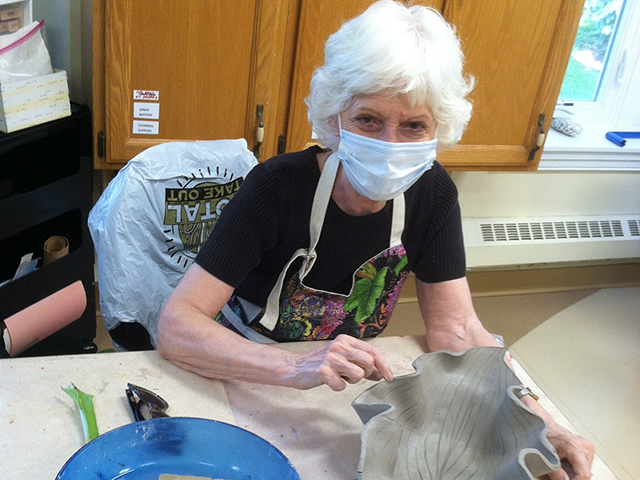 Woman with mask painting pottery