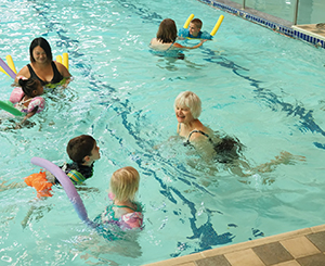 Group of residents and children swimming in community pool.